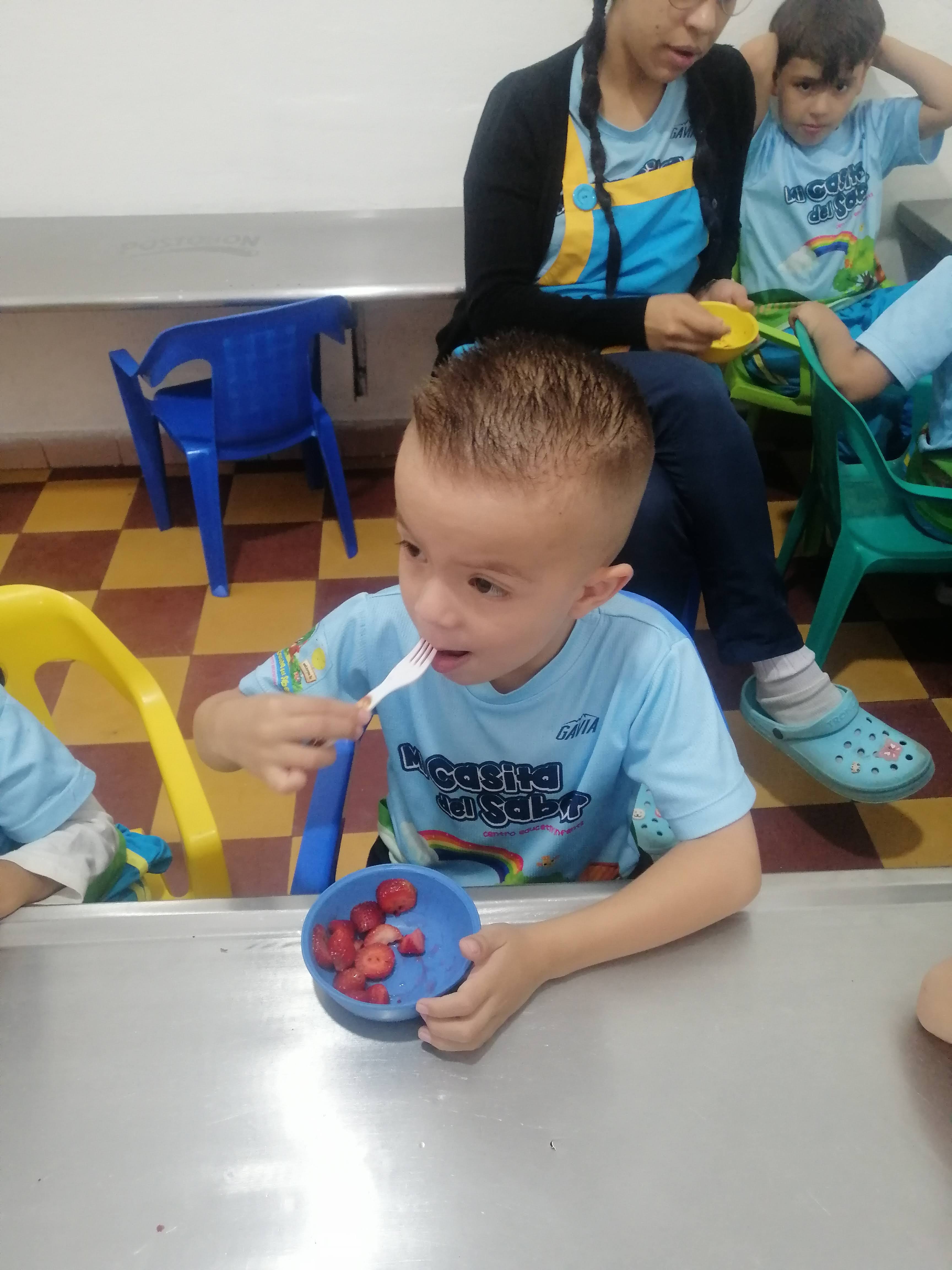 Niño disfrutando frutas frescas en el comedor